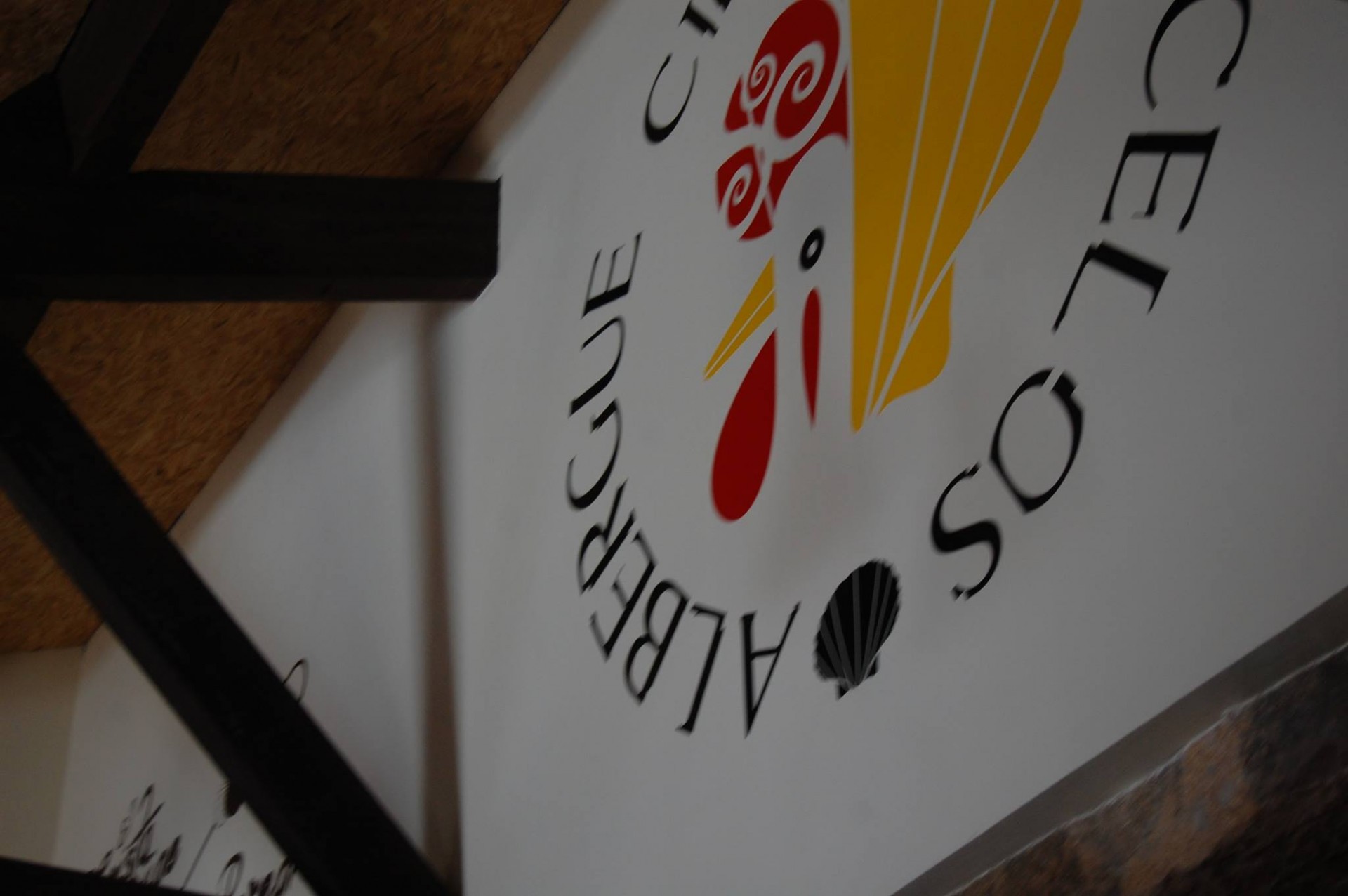 Rótulo branco com texto e desenho colorido numa parede com estrutura de madeira