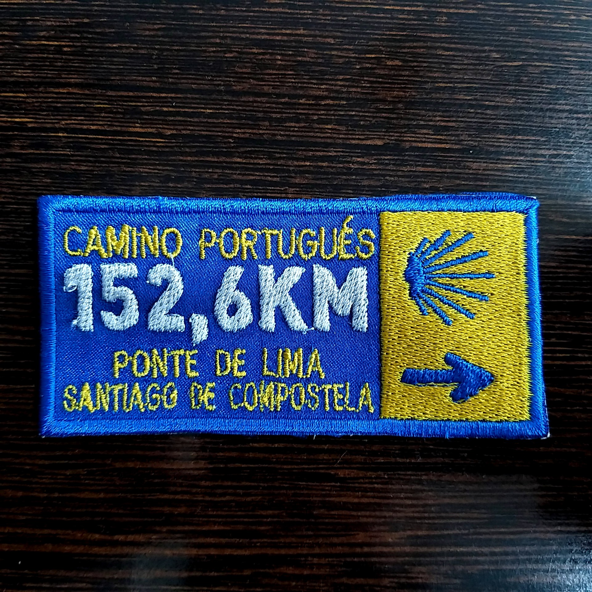 Emblema (Ponte de Lima) Emblema bordado retangular azul e amarelo com texto e símbolo de concha e seta