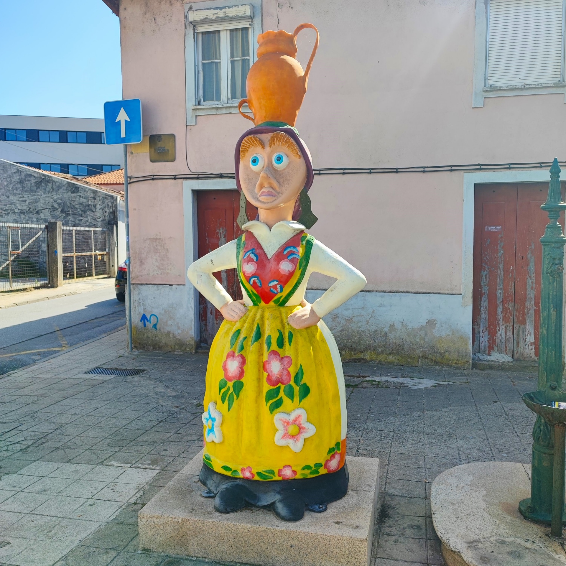 Estátua colorida de mulher com jarro na cabeça e vestido amarelo com flores