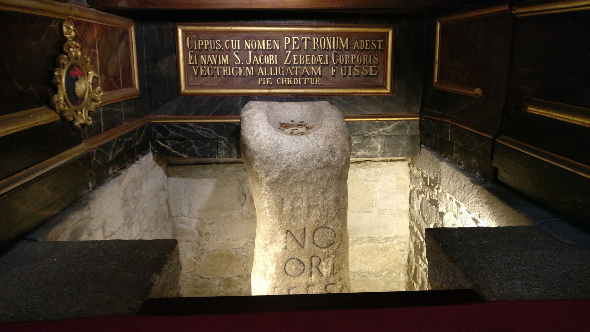 Marco miliário antigo em pedra com inscrições latinas em estrutura de pedra e madeira