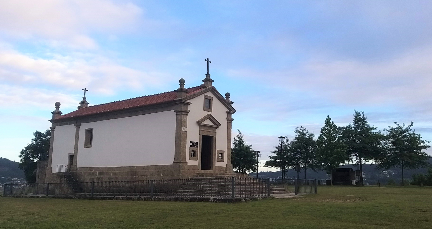 A Aparição a "João Mudo" no Caminho Português de Santiago Igreja pequena branca com pedras e telhado vermelho em espaço verde aberto