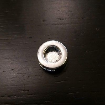 Pezinho de móvel redondo em metal prateado sobre madeira escura