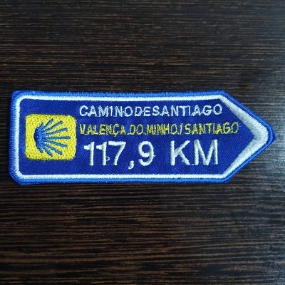 Emblema bordado do Camino de Santiago com texto em azul, branco e amarelo