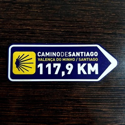 Etiqueta adesiva em forma de seta com indicação de distância e direção do Caminho de Santiago