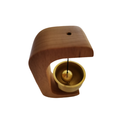 Pequeno sino dourado suspenso em estrutura de madeira clara curva