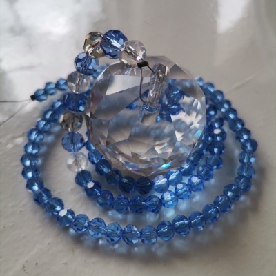Colar de contas azuis e transparentes enrolado em esfera de cristal facetada
