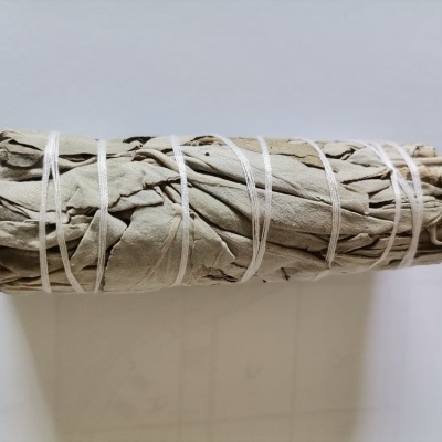 Maço de folhas secas amarradas com fios brancos sobre superfície branca