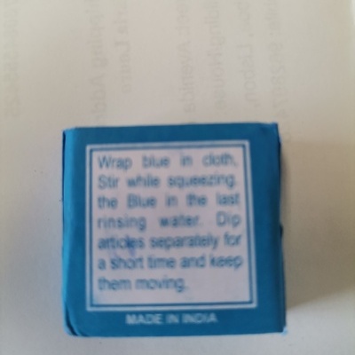 Pequena caixa azul com texto em inglês e 'MADE IN INDIA' em fundo branco