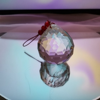 Pingente de cristal facetado com cordão e esferas vermelhas sobre espelho