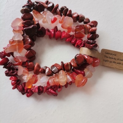 Pulseira de pedras naturais vermelhas, rosas e castanhas com etiqueta sobre fundo branco