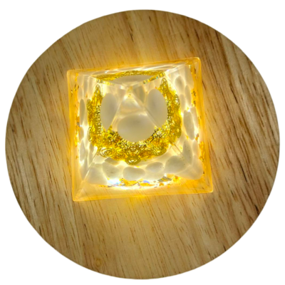 Peça decorativa quadrada transparente com detalhes dourados sobre madeira clara