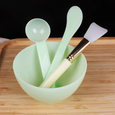 Conjunto de utensílios para máscara facial verde claro numa taça sobre base de madeira