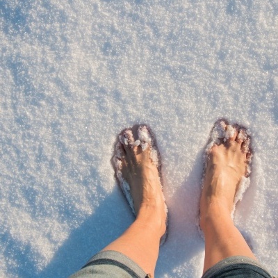 Pés descalços na neve com calças jeans enroladas