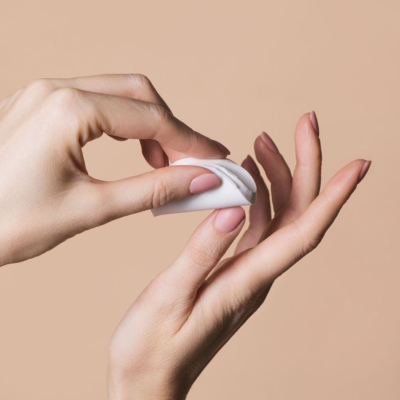 Mãos femininas a segurar disco de algodão branco