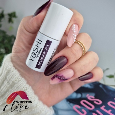 Mão com unhas decoradas segurando verniz para unhas YOSHI WRITTEN