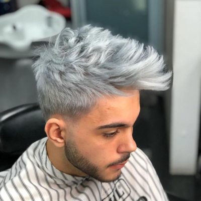 Homem com cabelo cinza curto, laterais raspadas e barba, em cadeira de barbeiro