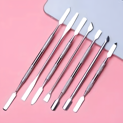 Seis espátulas metálicas num fundo rosa