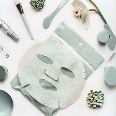 Máscara facial branca com acessórios cosméticos e planta suculenta em fundo branco