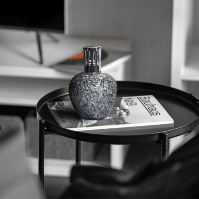 Vaso cerâmico craquelado cinza e preto sobre mesa preta com livros