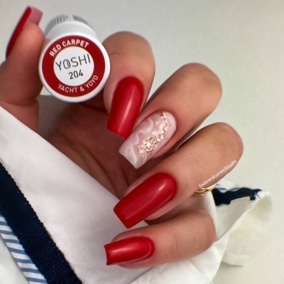 Unhas compridas vermelhas foscas e bege com brilho segurando frasco de esmalte