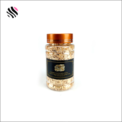 Frasco plástico com tampa laranja e rótulo preto contendo flocos dourados