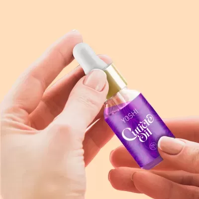 Frasco de óleo para cutículas YOSHI Cuticle Oil segurado por mãos