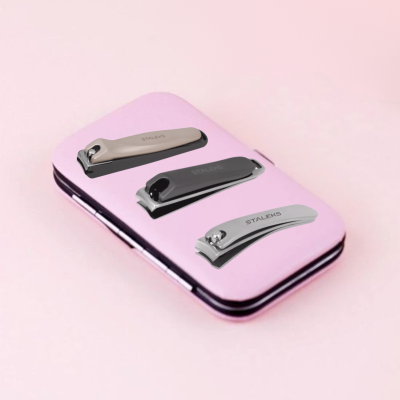 Três corta-unhas metálicos STALEKS sobre caixa rosa