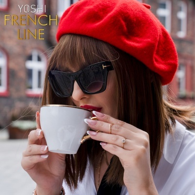 Mulher com boina vermelha, óculos de sol pretos e chávena de café branca em ambiente urbano