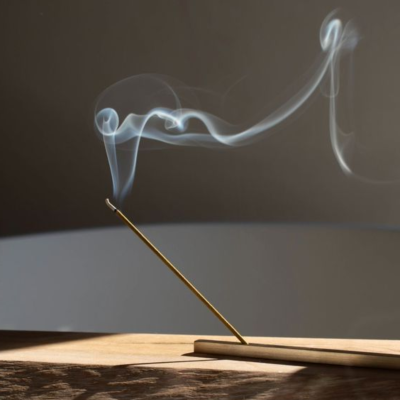 Incenso dourado aceso com fumo numa base de madeira