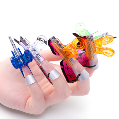 Mão com prensadores de unhas coloridos e transparentes em fundo branco.