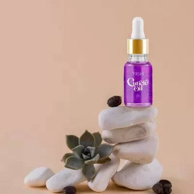 Frasco de óleo para cutículas roxo com conta-gotas em pedras brancas com planta e grãos de café