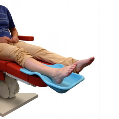 Suporte para pés azul numa cama hospitalar vermelha com pernas expostas de pessoa sentada.