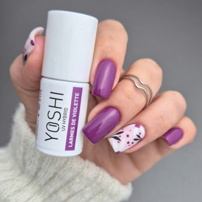 Frasco de verniz YOSHI UV HYBRID com unhas roxas e decoração floral