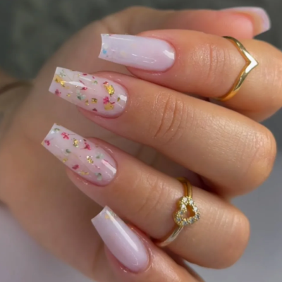 Unhas artificiais rosa claro com brilho e anéis dourados