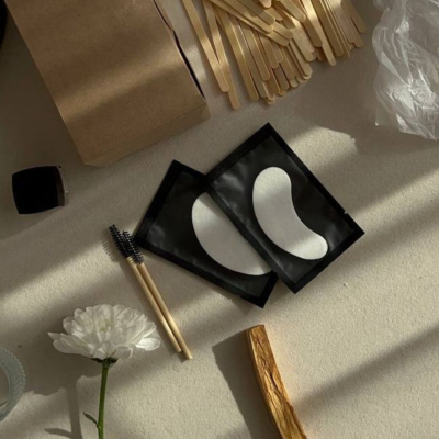 Produtos de beleza e cuidados em superfície clara com acessórios de madeira e flor branca