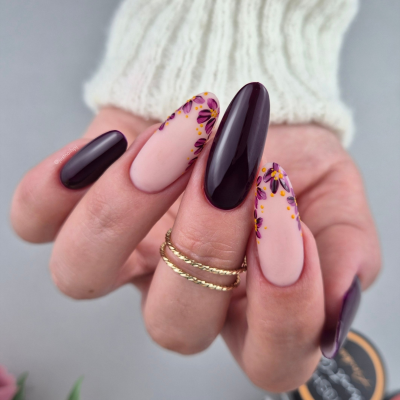 Unhas pintadas vinho e rosa com flores roxas e amarelas, anéis dourados, casaco branco de malha