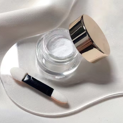 Frasco de vidro com pó branco e aplicador sobre fundo branco