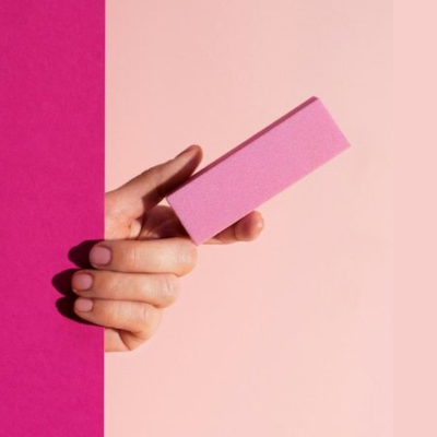 Mão segurando uma lima de unha rosa