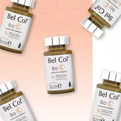 Frascos pequenos de vidro âmbar de fluído de vitamina C Bel Col Bio C sobre fundo rosa