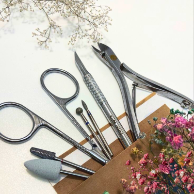 Ferramentas de manicure e pedicure em metal prateado com flores secas