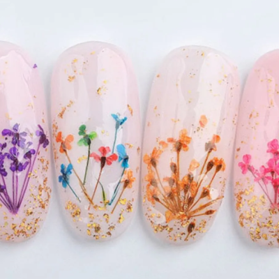Unhas postiços decoradas com flores coloridas secas e brilhos dourados