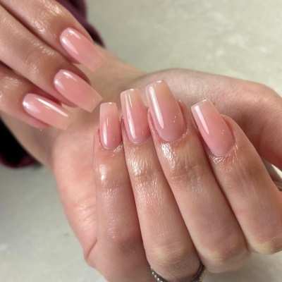 Unhas artificiais quadradas pintadas de rosa translúcido brilhante em mãos femininas