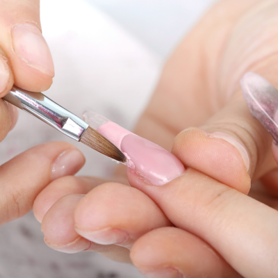 pincel a aplicar verniz de gel rosa numa unha