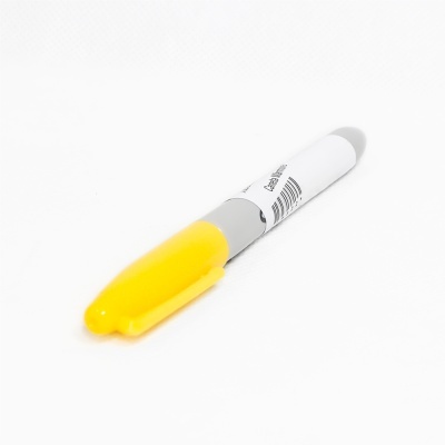 Caneta permanente com tampa amarela sobre superfície branca