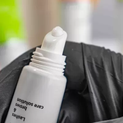 Tubo branco com ponta aplicadora segurado por mão com luva preta