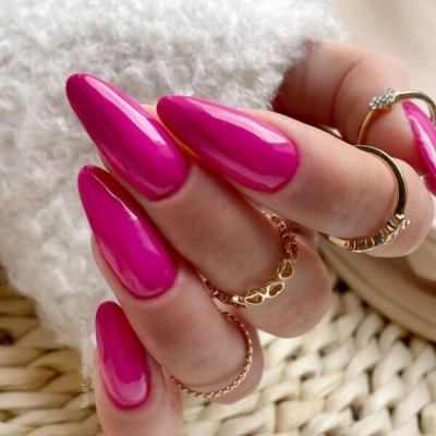 Unhas artificiais rosas brilhantes com anéis dourados e fundo têxtil branco