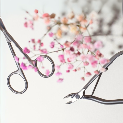 Ferramentas de manicure metálicas com flores cor-de-rosa desfocadas