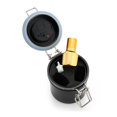 recipiente preto com tampa prateada aberta e frasco dourado no interior