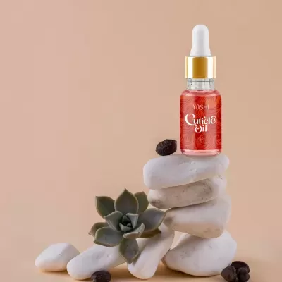 Frasco de óleo para cutículas vermelho em pedras brancas empilhadas com planta suculenta e grãos escuros