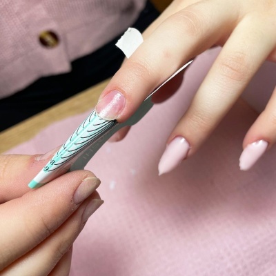Unhas femininas a ser moldadas com forma plástica para unhas em gel